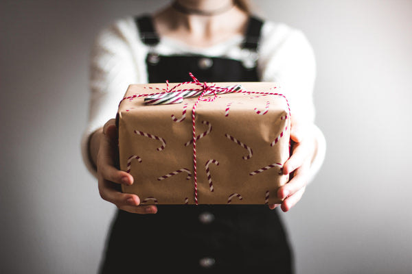 15 achtsame Geschenke unterm Weihnachtsbaum - Frau hält verpacktes Geschenk